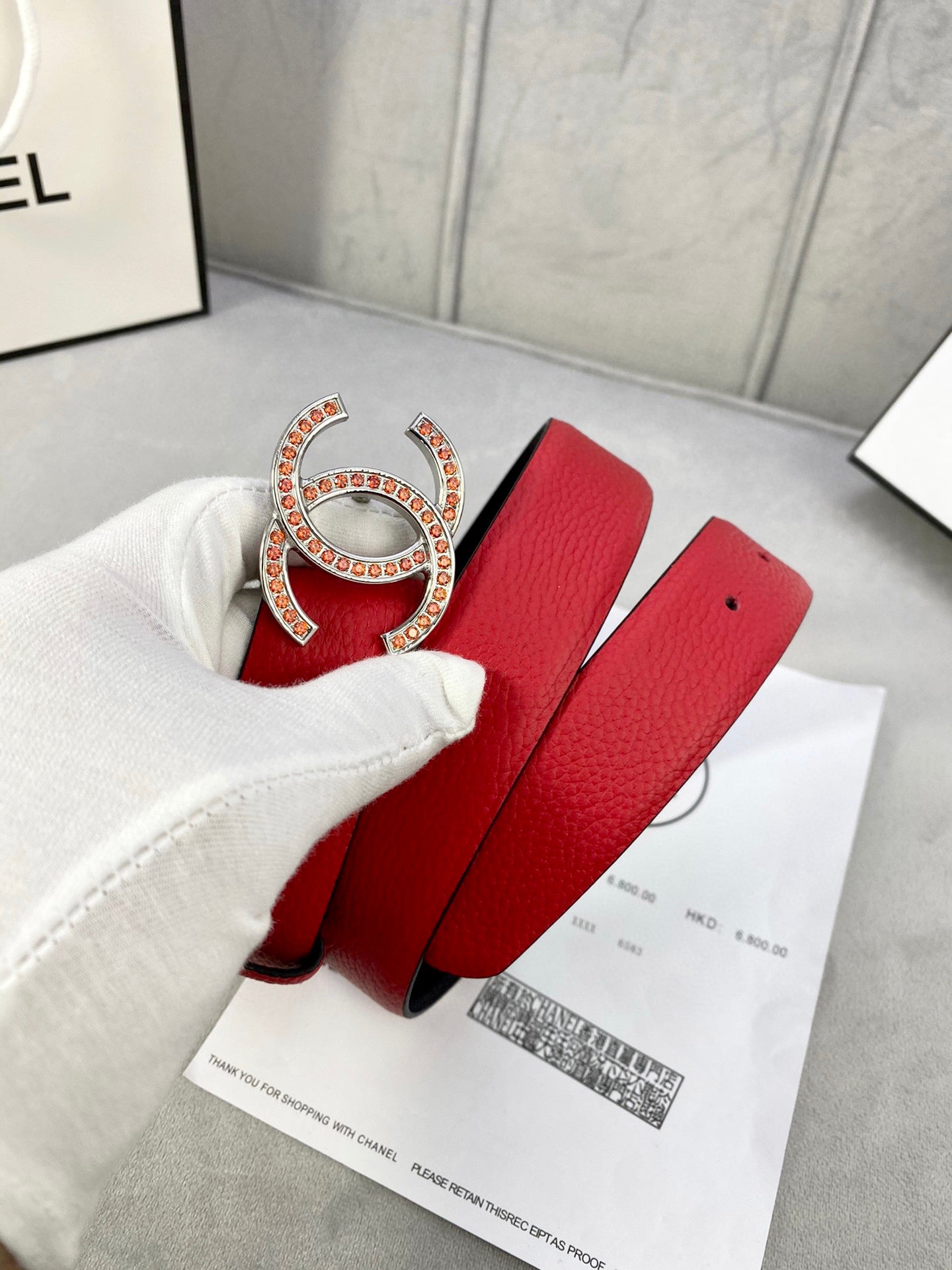 Red leather belt with large gold-tone Chanel CC buckle and matching pin holes.