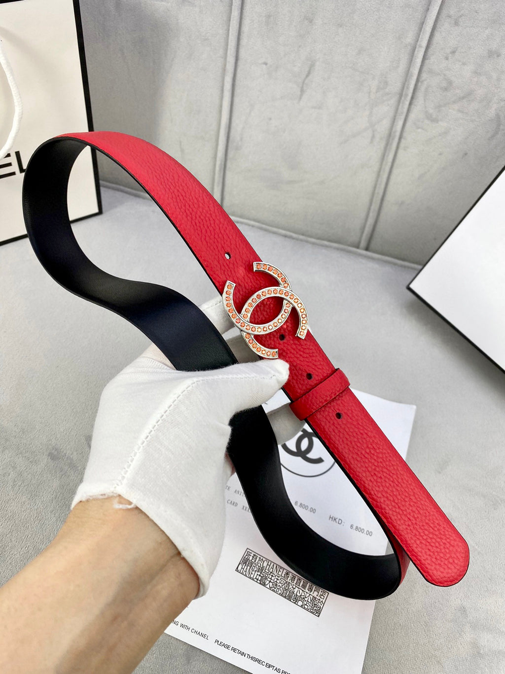 Red leather belt with gold-tone Chanel CC buckle, wide strap shown with black backing.