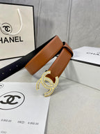 Tan leather belt with rhinestone CC buckle, laid across white packaging