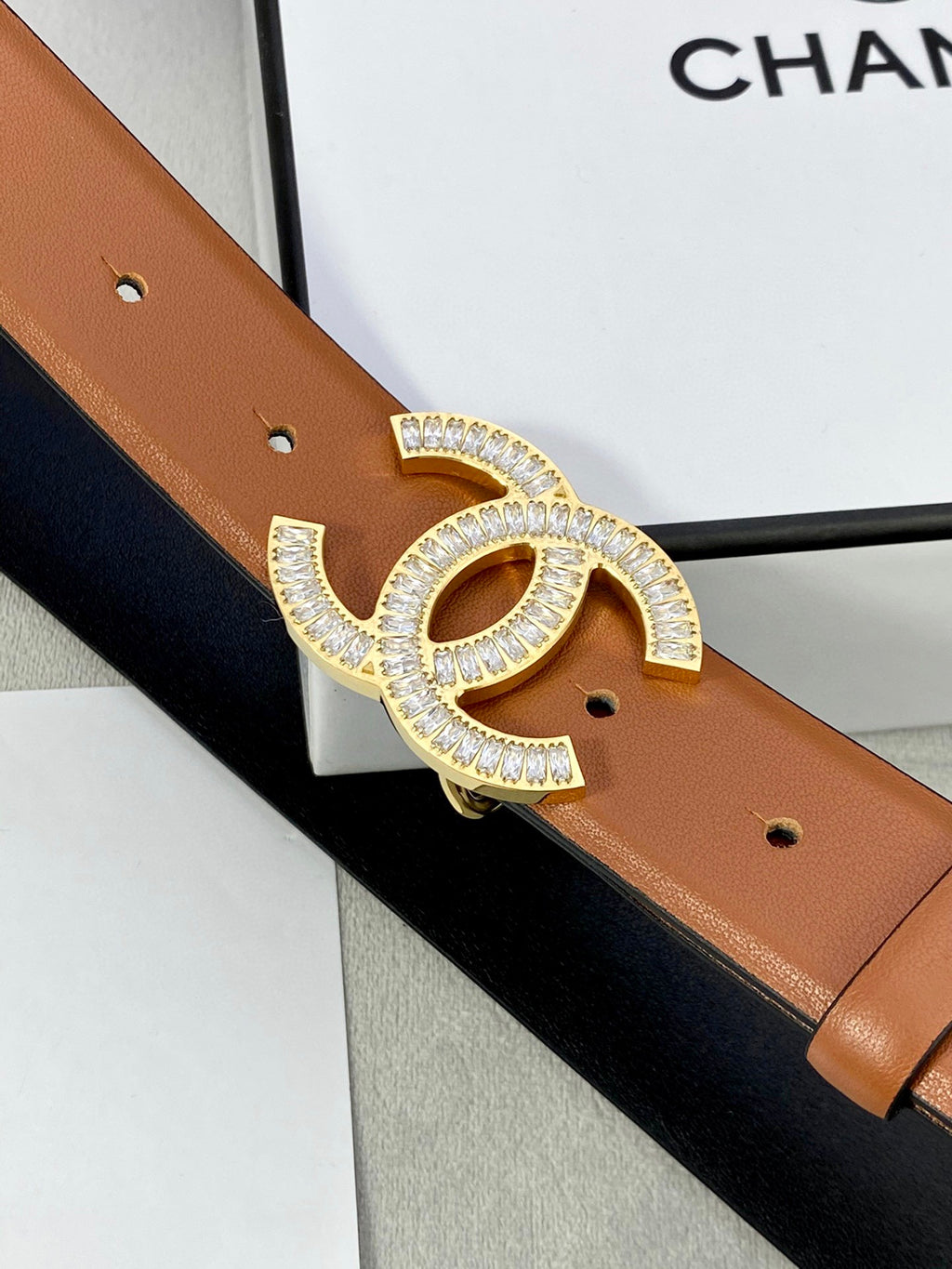 Close-up Chanel belt with rhinestone CC buckle on tan leather strap