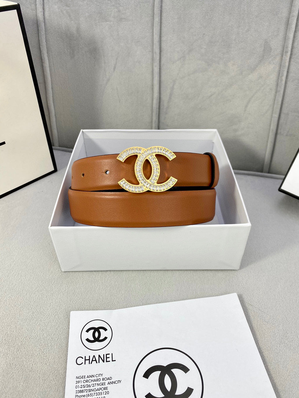 Tan leather belt with rhinestone CC buckle in a white gift box