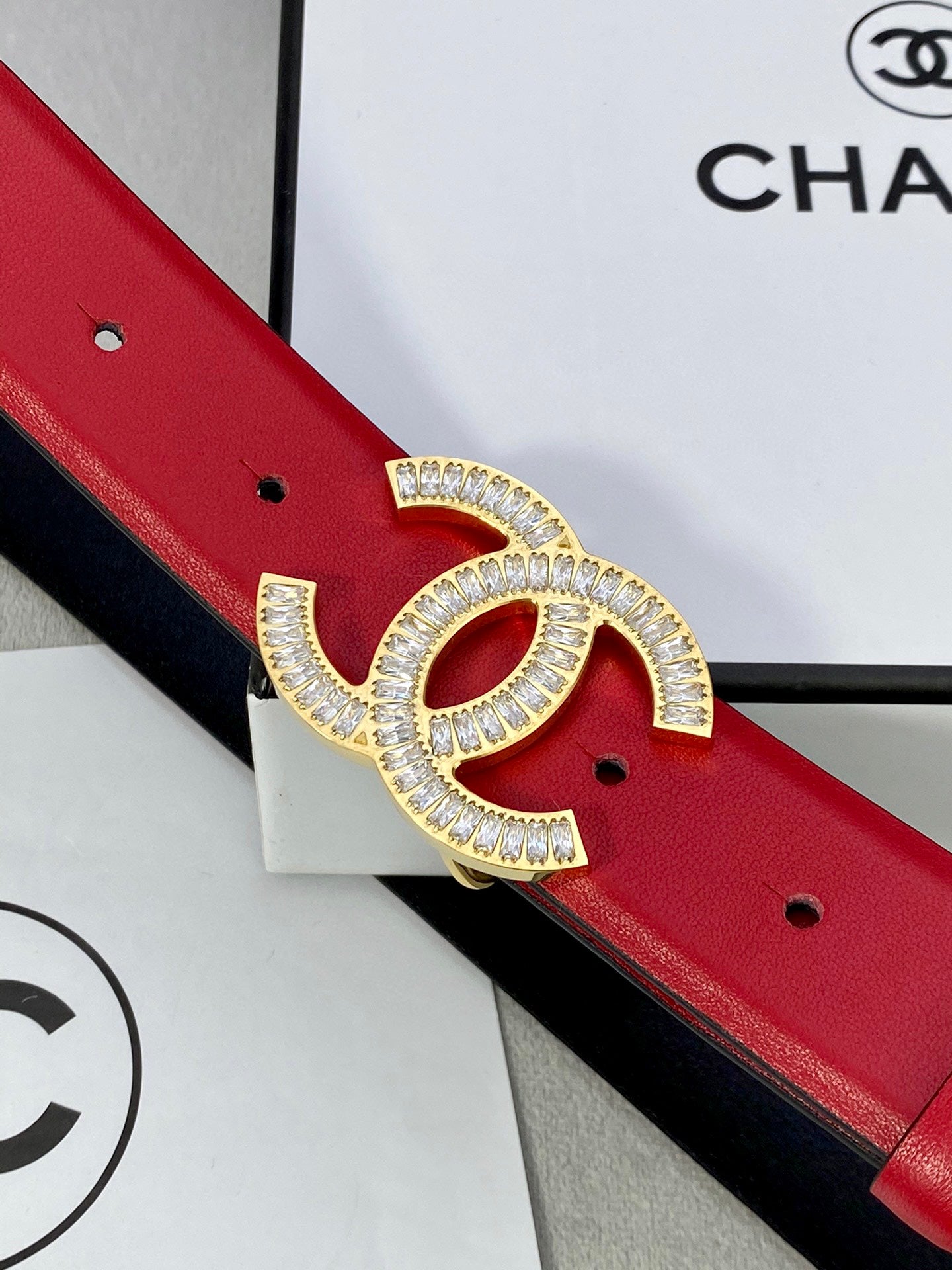 Close-up of red leather belt with Chanel gold-tone double C buckle ornament