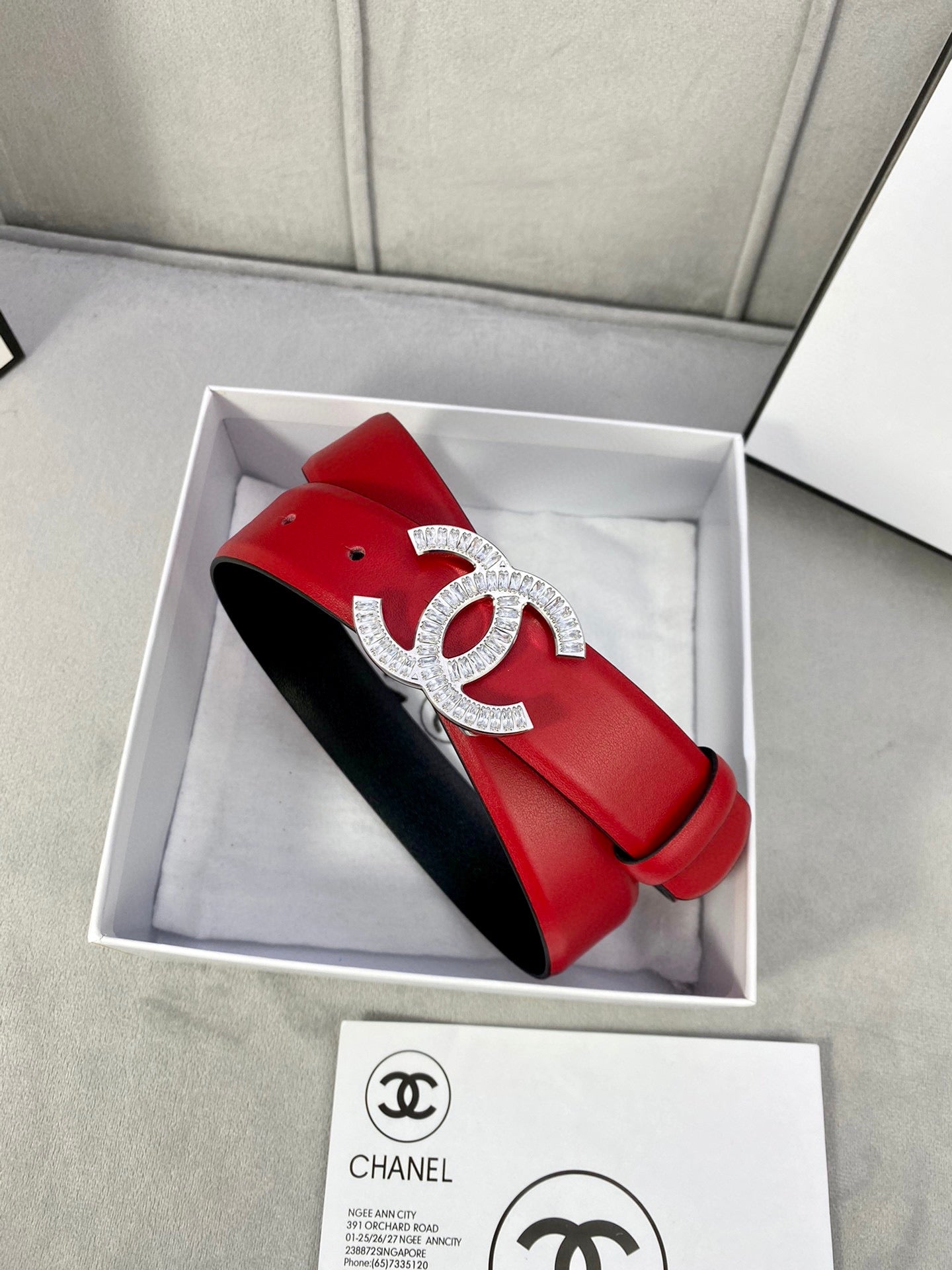 Red leather belt with Chanel gold-tone double C buckle, nestled in a gift box