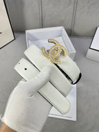 White leather belt with gold-tone rhinestone CC buckle, lying across box insert