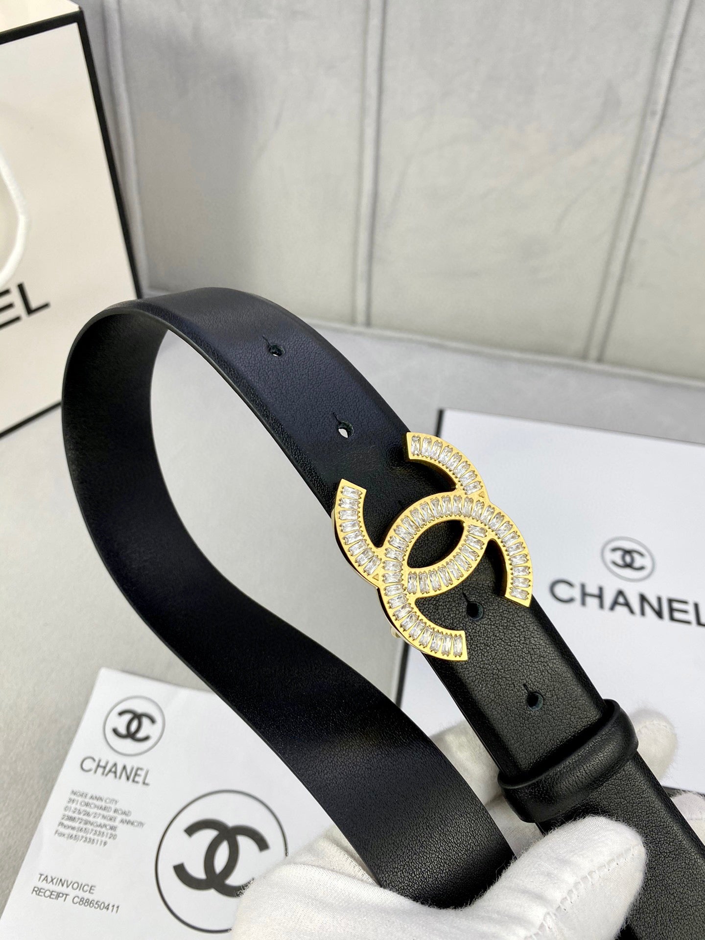 Black leather belt with rhinestone CC buckle on the strap, angled view