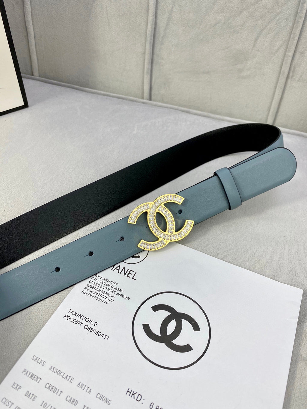 Light blue Chanel belt on a flat surface with gold CC buckle detail.