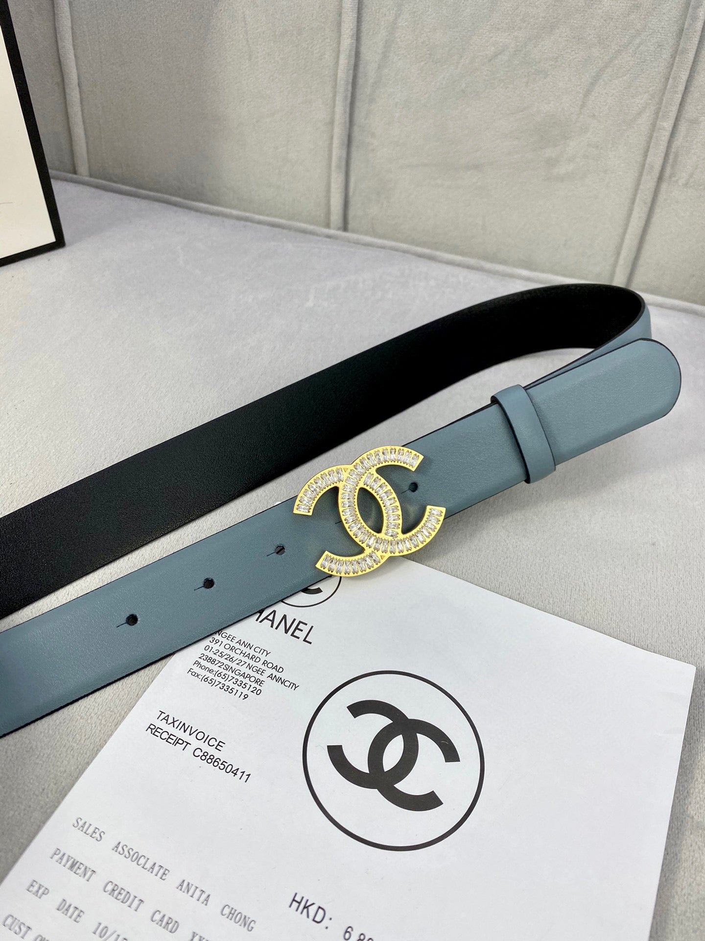 Light blue Chanel belt on a flat surface with gold CC buckle detail.