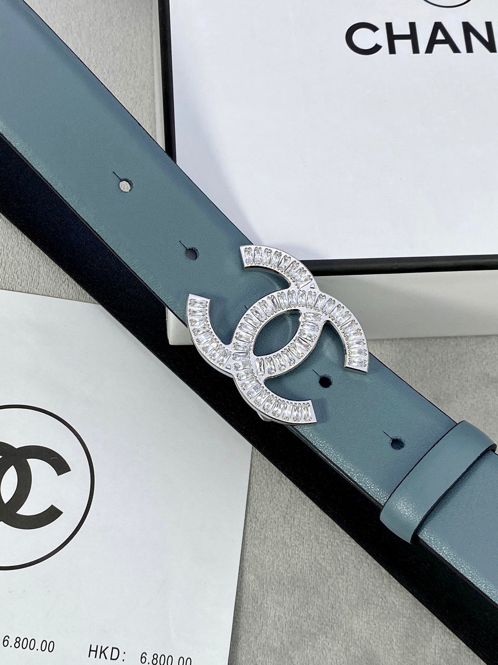 Close-up of light blue Chanel belt with silver-toned CC buckle and holes.