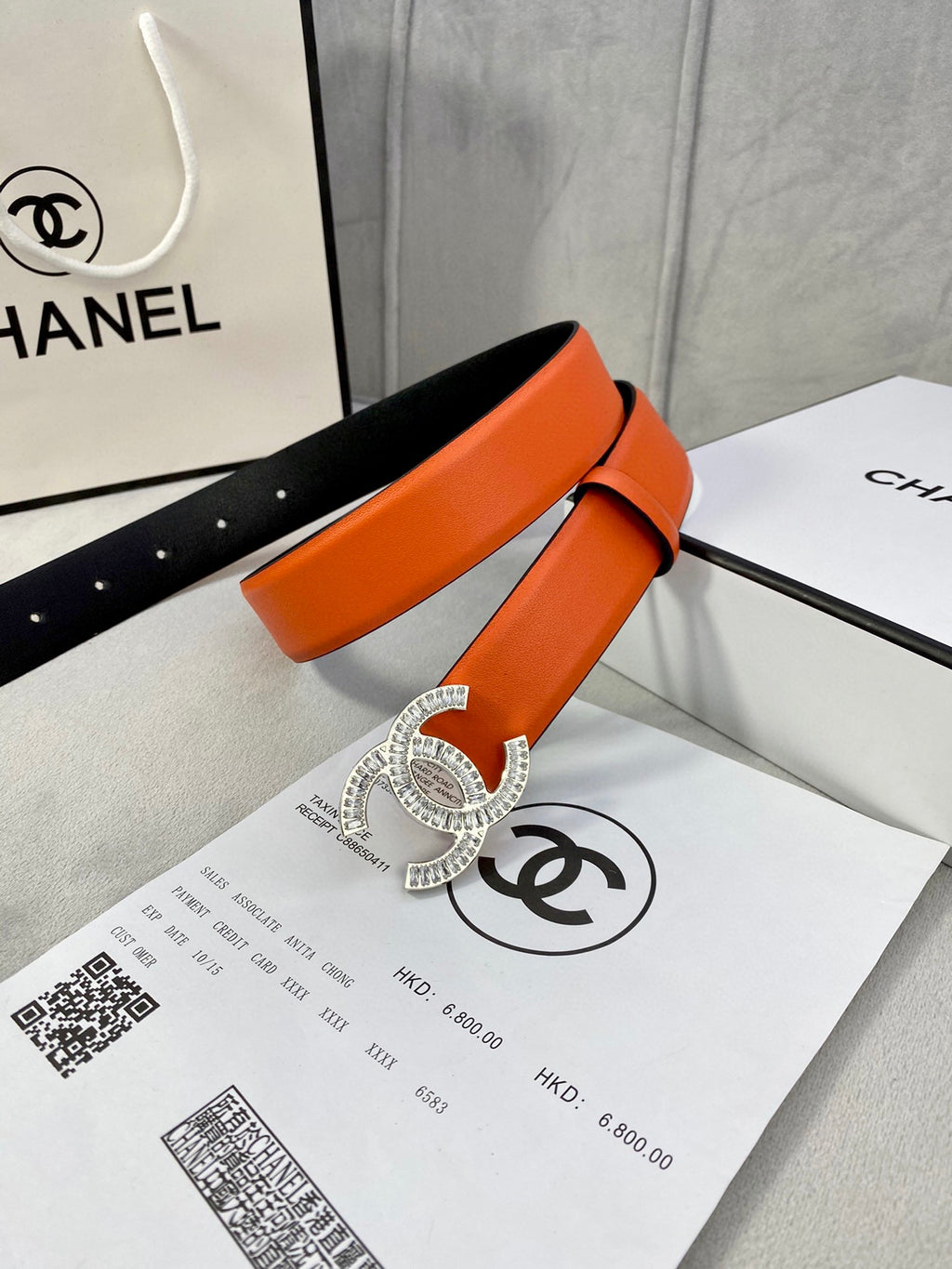 Chanel orange belt with crystal buckle and adjustable holes over black lining