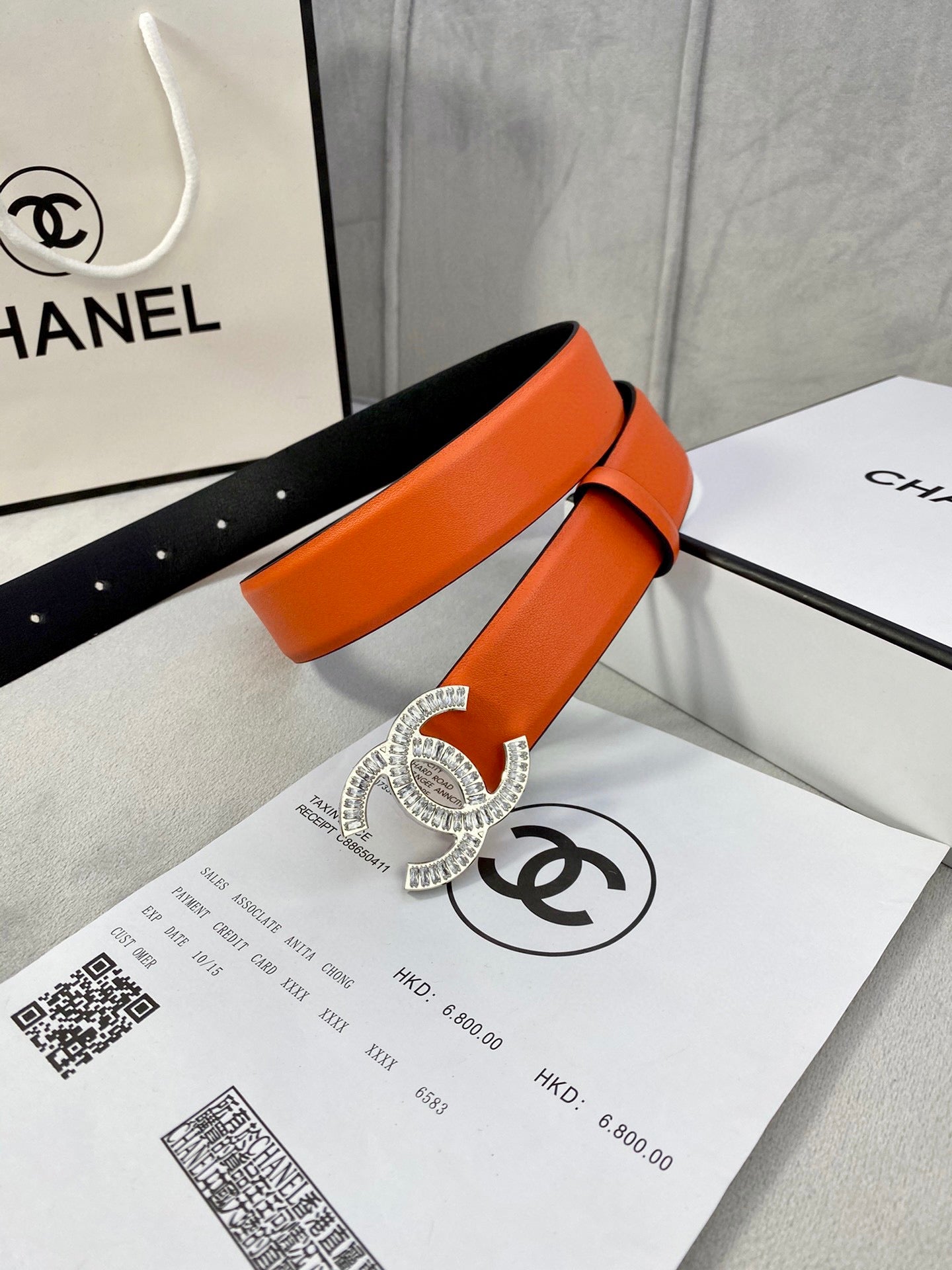 Chanel orange belt with crystal buckle and adjustable holes over black lining