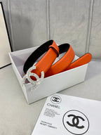 Chanel orange belt with large crystal CC buckle, resting on box and papers