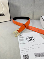 Chanel orange belt with black underside and crystal CC buckle, shown on packaging
