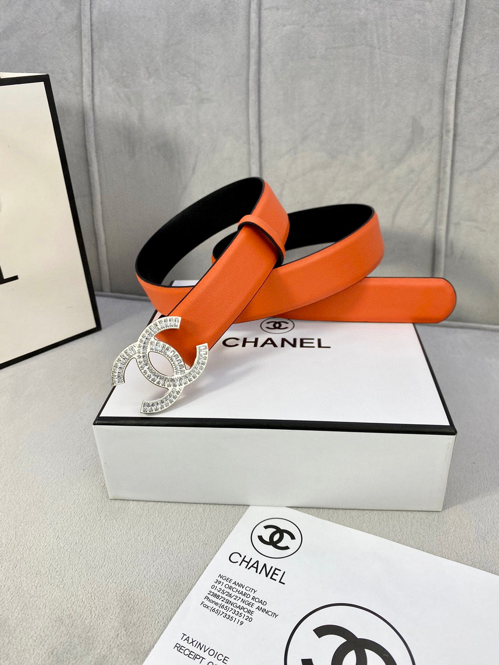 Chanel orange belt with crystal CC buckle, shown with black-lined side