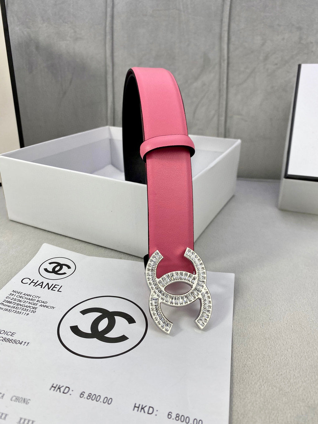 Chanel belt with pink leather strap, black lining, and rhinestone CC buckle