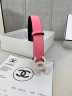 Chanel belt with pink leather strap, black lining, and rhinestone CC buckle