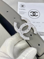 Chanel belt buckle close-up with rhinestone CC design on light gray leather