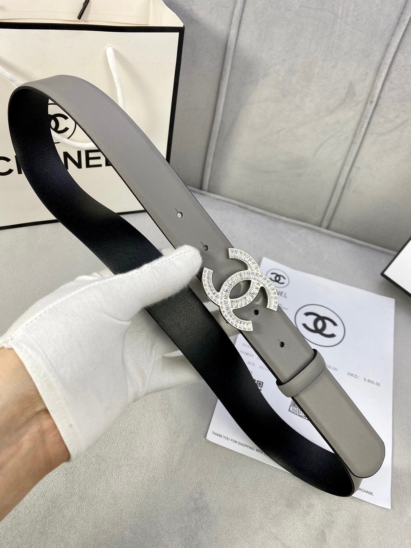 Chanel belt held with light gray strap and silver-toned CC buckle, close view