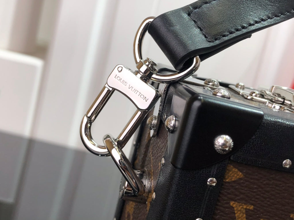Louis Vuitton bag strap hardware with metal rings, clips, and black leather tab