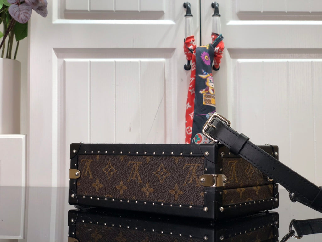 Monogram canvas bag with black leather shoulder strap and silver corner studs.