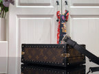 Monogram canvas bag with black leather shoulder strap and silver corner studs.