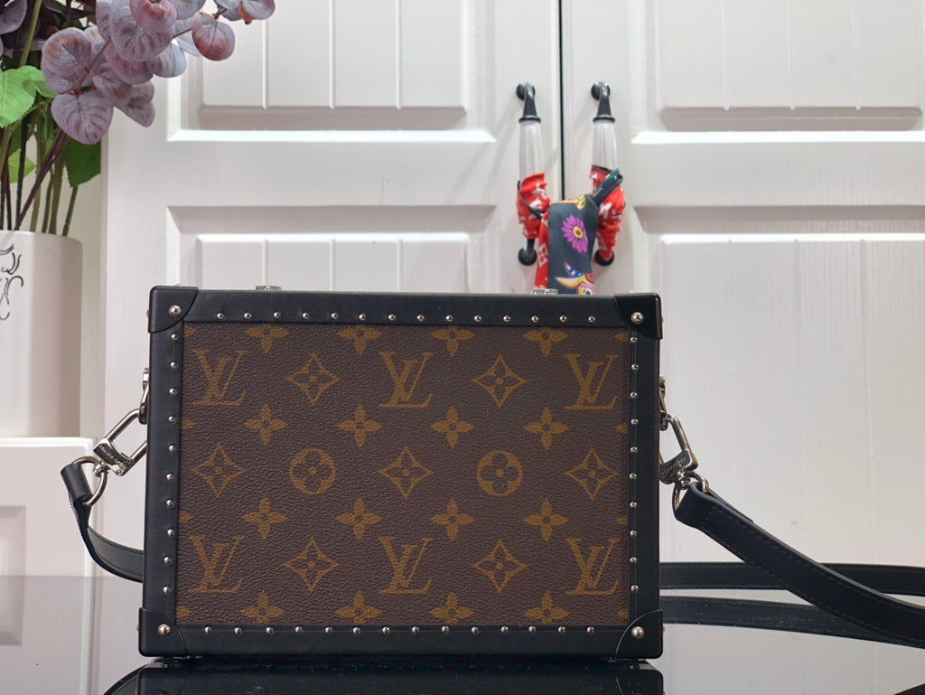 Monogram canvas crossbody bag with black leather trim, silver studs, front flap.