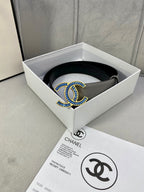 Grey leather belt laid in box, featuring a blue-and-gold CC buckle