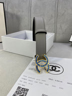 Grey leather belt with blue-and-gold CC buckle, close-up view
