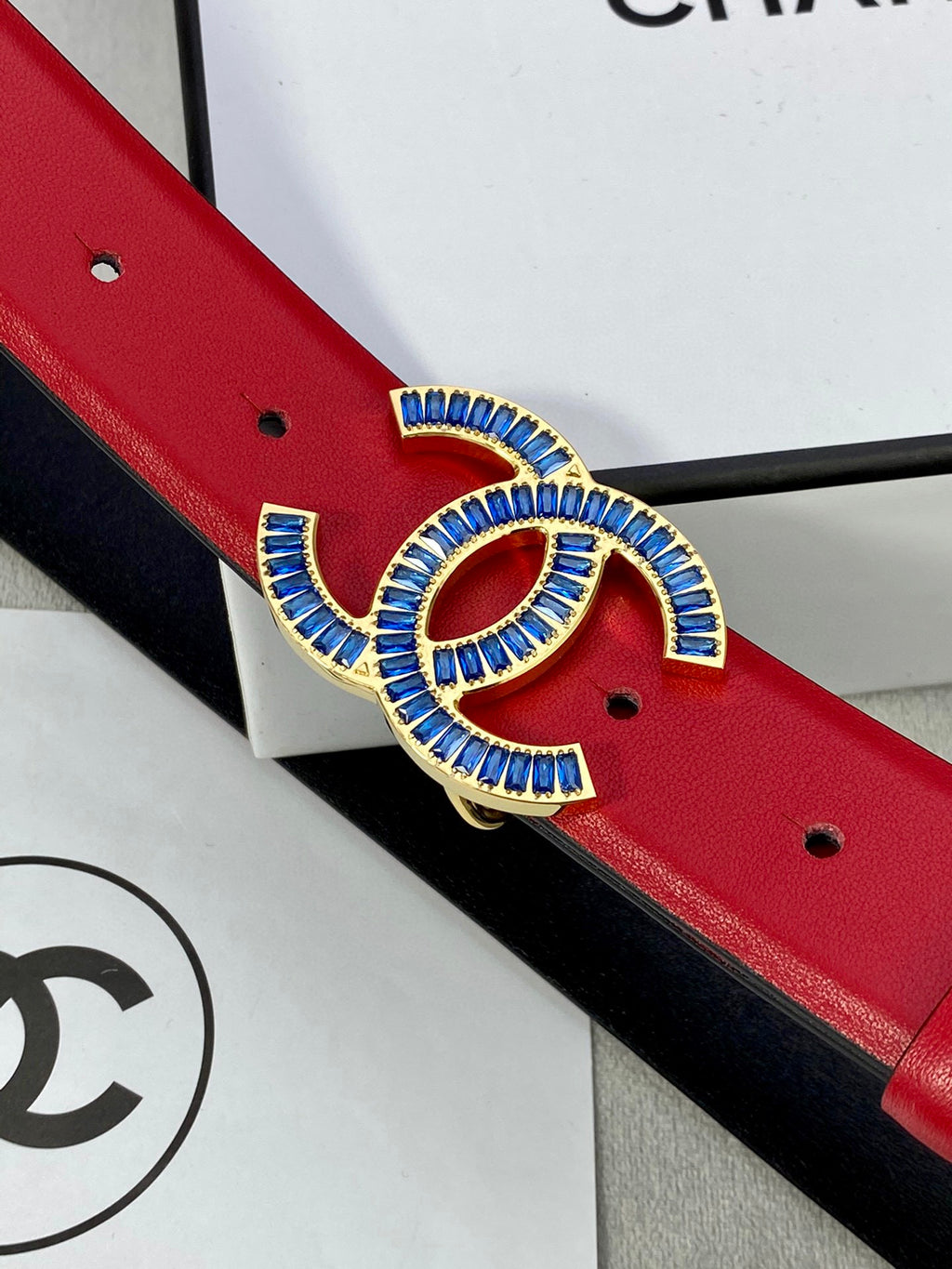 Blue-and-gold CC logo buckle on red leather belt with round pin holes