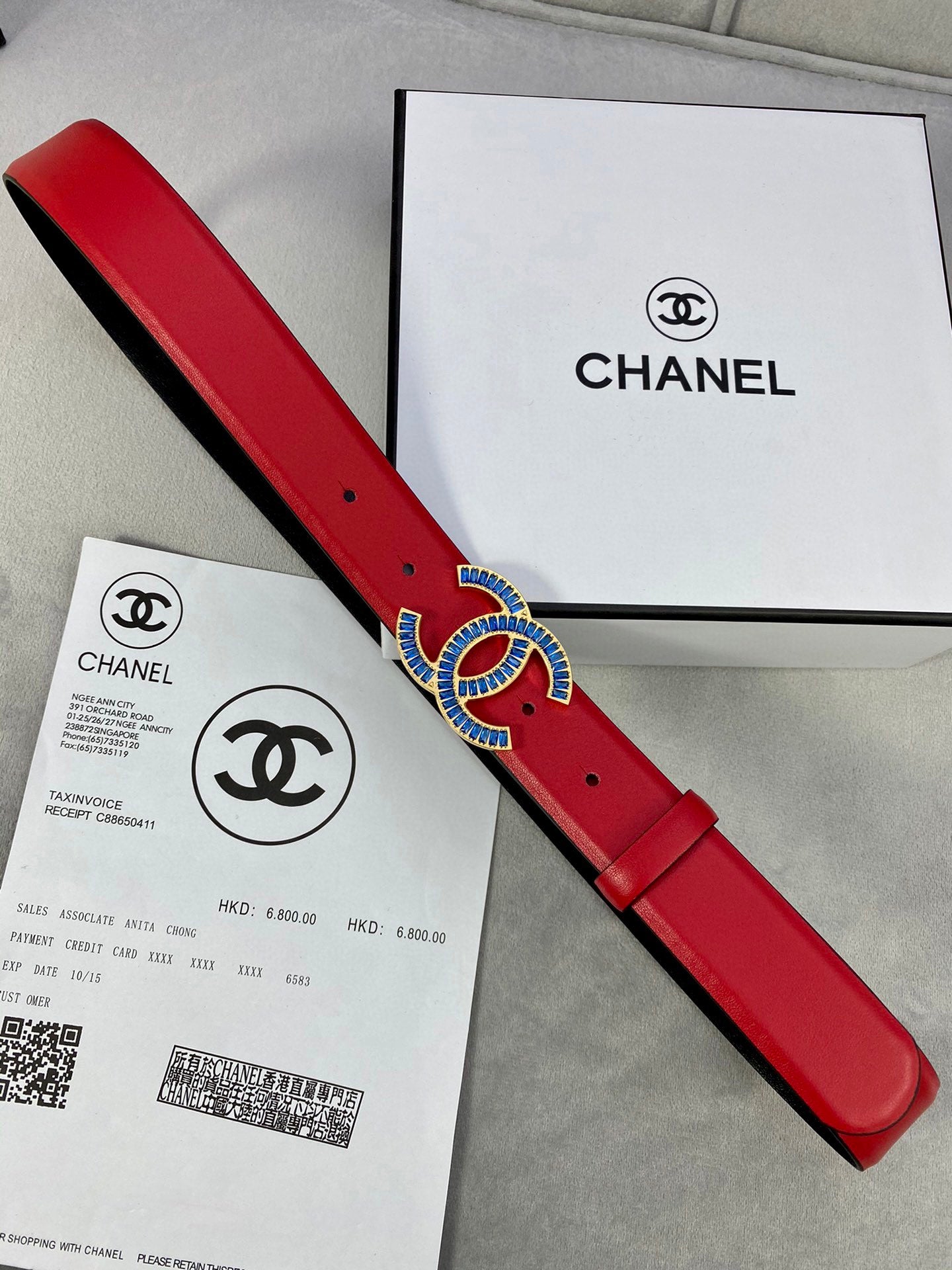 Long red leather belt with blue-and-gold CC logo buckle and adjustable pin holes