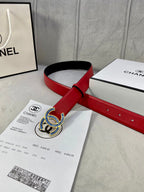 Red and black leather belt with blue-and-gold CC logo buckle on accessory papers