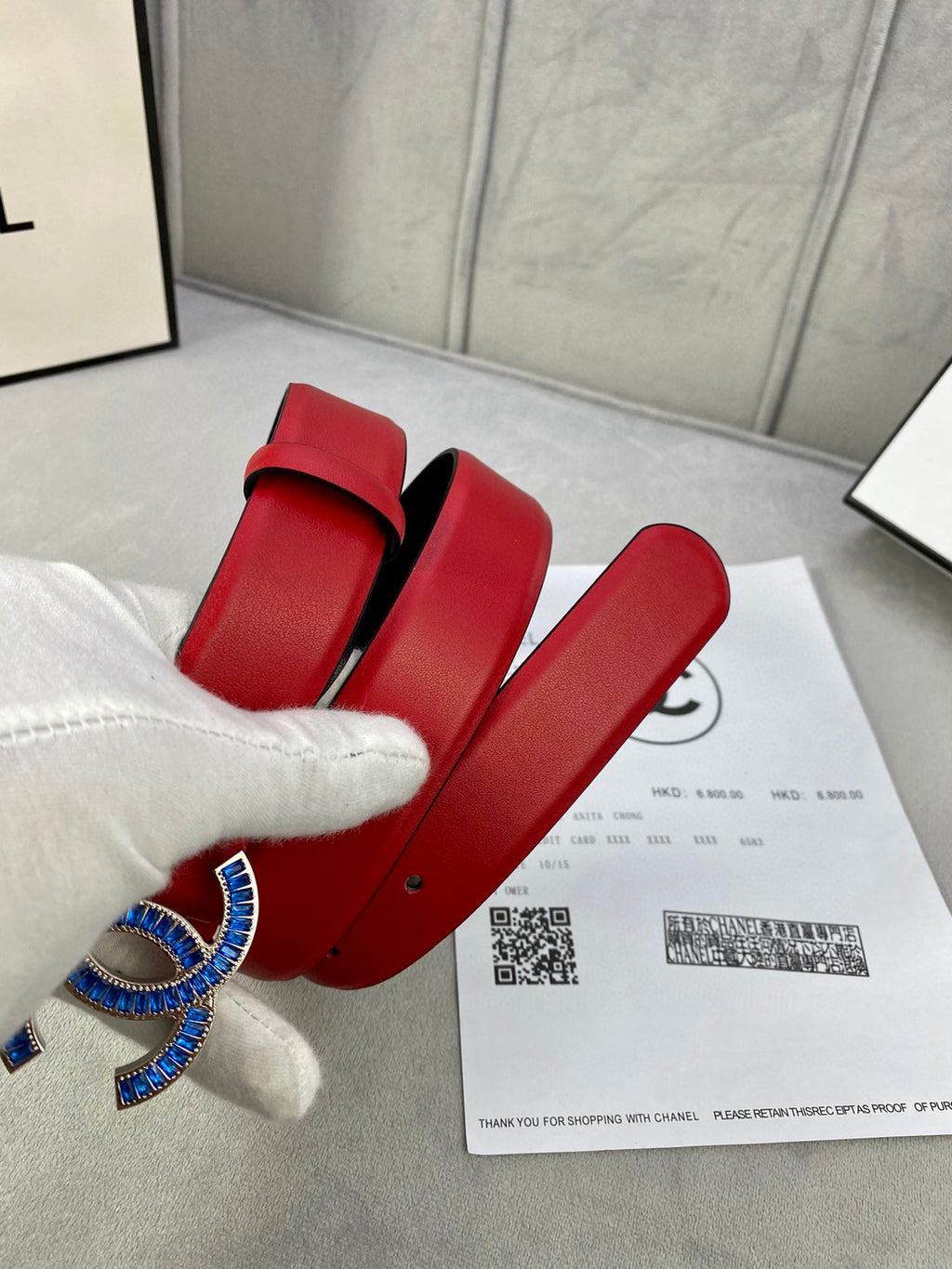Red leather belt with blue-and-gold CC logo buckle and adjustable pin-hole strap