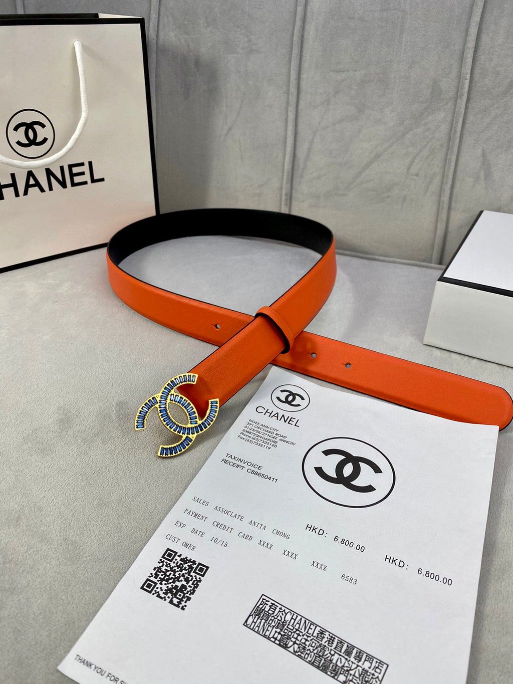 Orange leather belt with blue CC logo buckle and pin holes