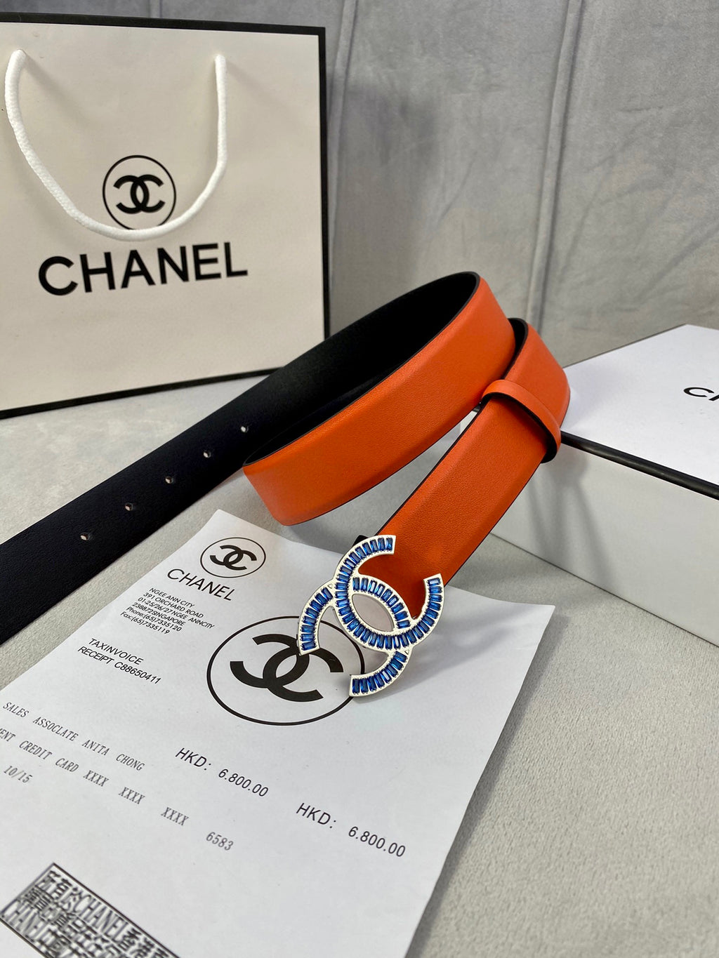 Orange leather belt with blue CC buckle and black inner side