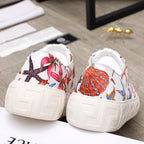 Pair white low-top sneakers with colorful starfish sea-life print, white laces, chunky sole.