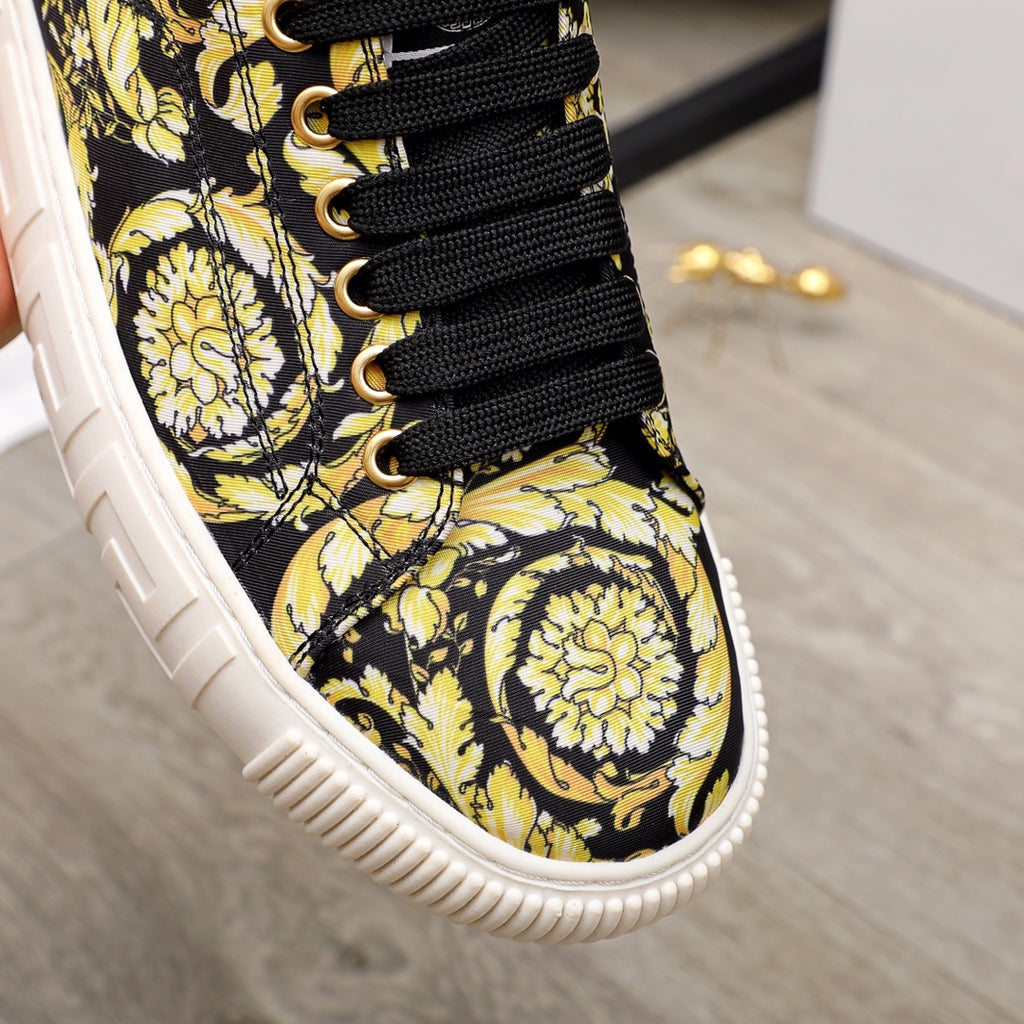 Versace luxury sneaker close-up of lace-up front, black laces on black-and-yellow baroque fabric