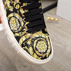 Versace luxury sneaker close-up of lace-up front, black laces on black-and-yellow baroque fabric