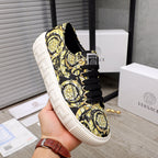 Versace luxury sneaker on hand, black-and-yellow baroque print, black laces, white textured sole