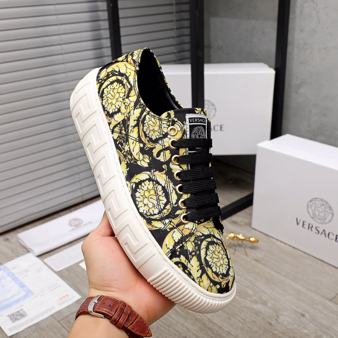 Versace luxury sneaker on hand, black-and-yellow baroque print, black laces, white textured sole