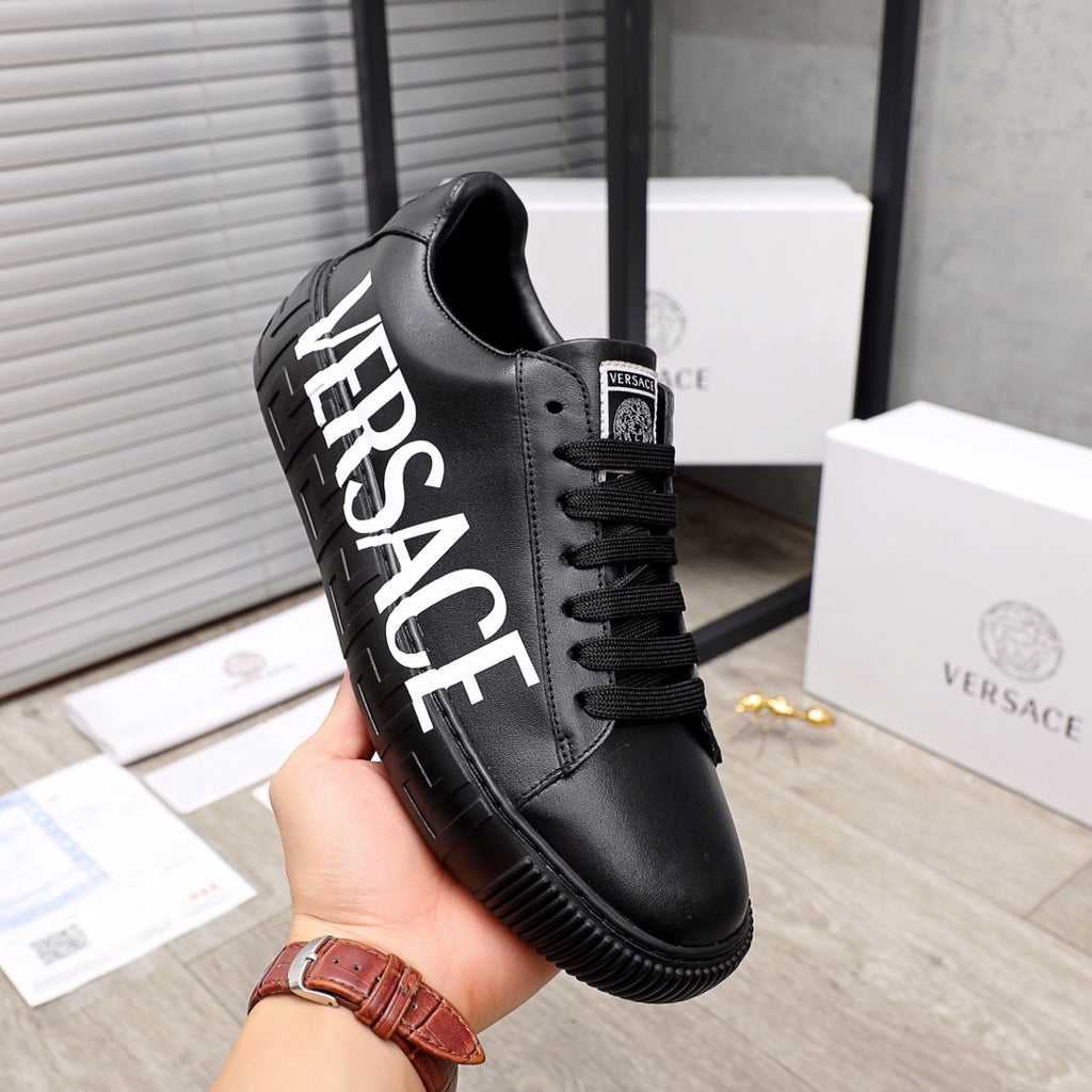Black low-top sneakers with oversized white side lettering and lace-up closure
