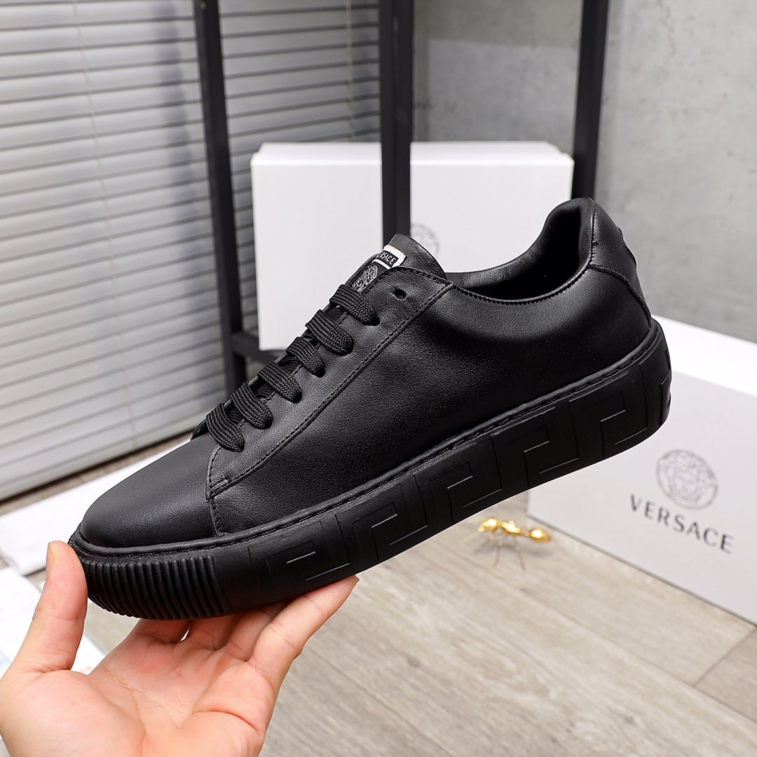 Black low-top sneakers with black rubber tread sole and lace-up front