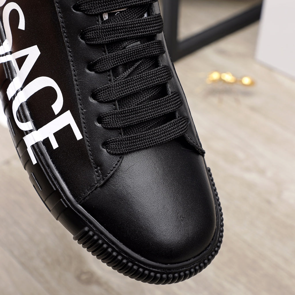 Close-up of black lace-up sneaker with textured stitching and black rubber sole