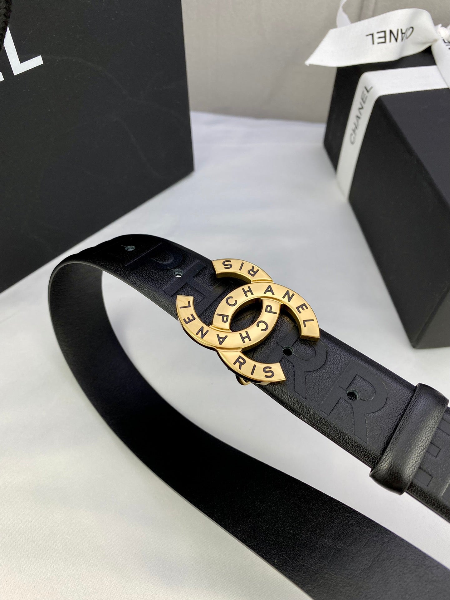 Chanel belt close-up: dark embossed strap with gold-tone circular logo buckle