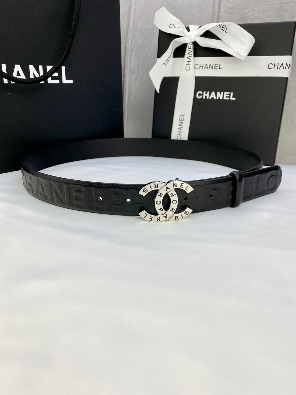 Chanel belt with dark textured strap and round gold-tone logo buckle
