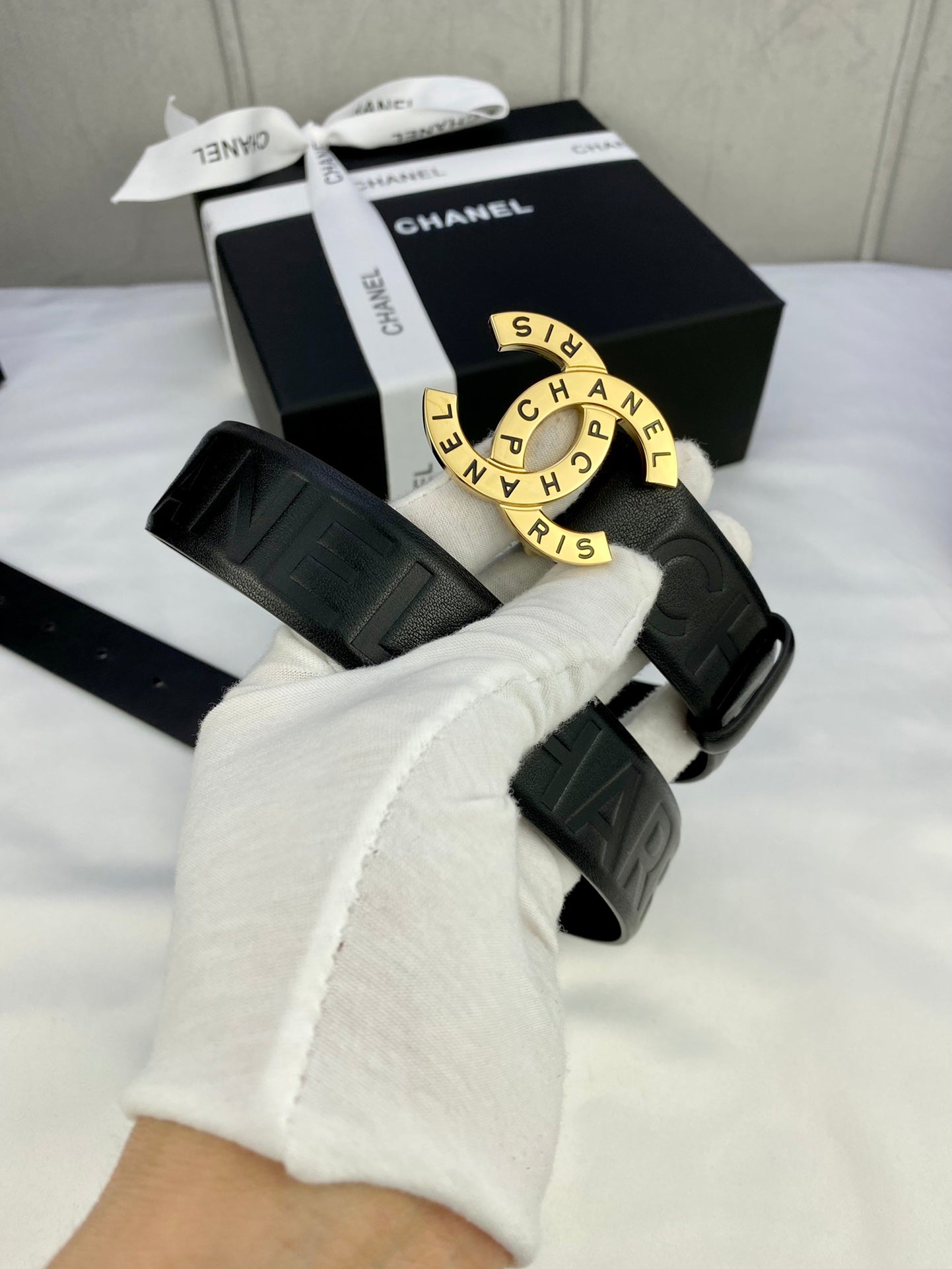Chanel belt on arm: dark embossed strap with round gold-tone CHANEL buckle