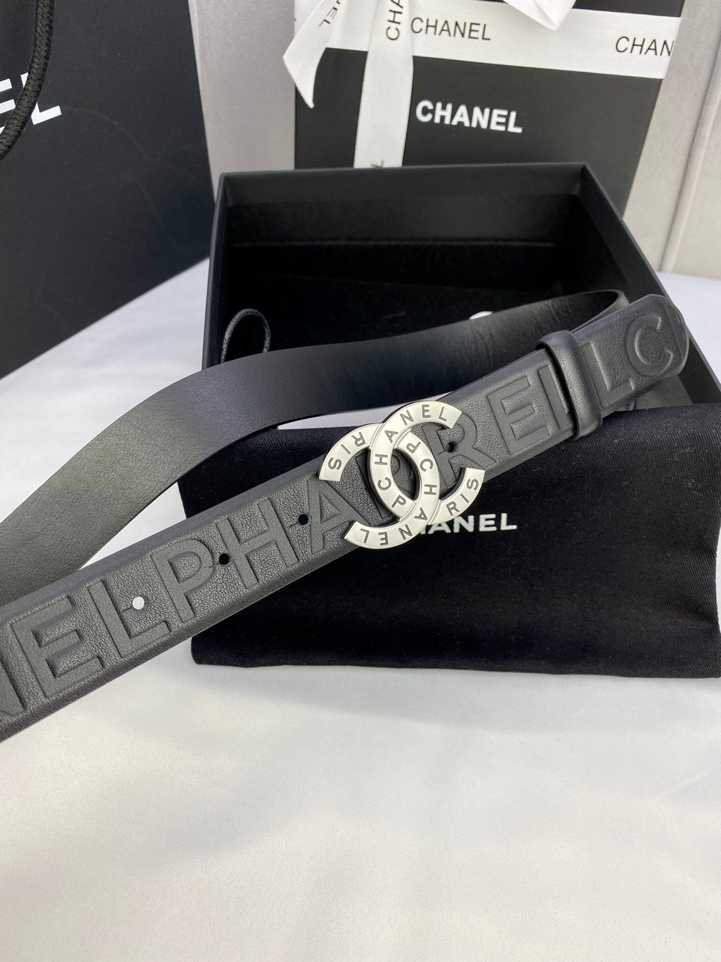 Chanel belt detail: dark embossed strap with round gold-tone CHANEL buckle