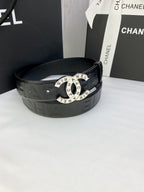 Chanel belt on display: dark strap with embossed pattern and gold-tone logo buckle