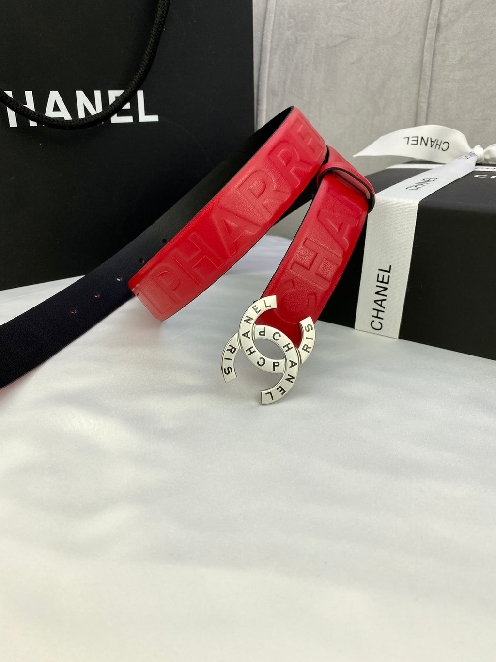 Red Chanel belt with embossed strap and gold circular CHANEL buckle on display box