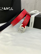 Red Chanel belt with embossed strap and gold circular CHANEL buckle on display box
