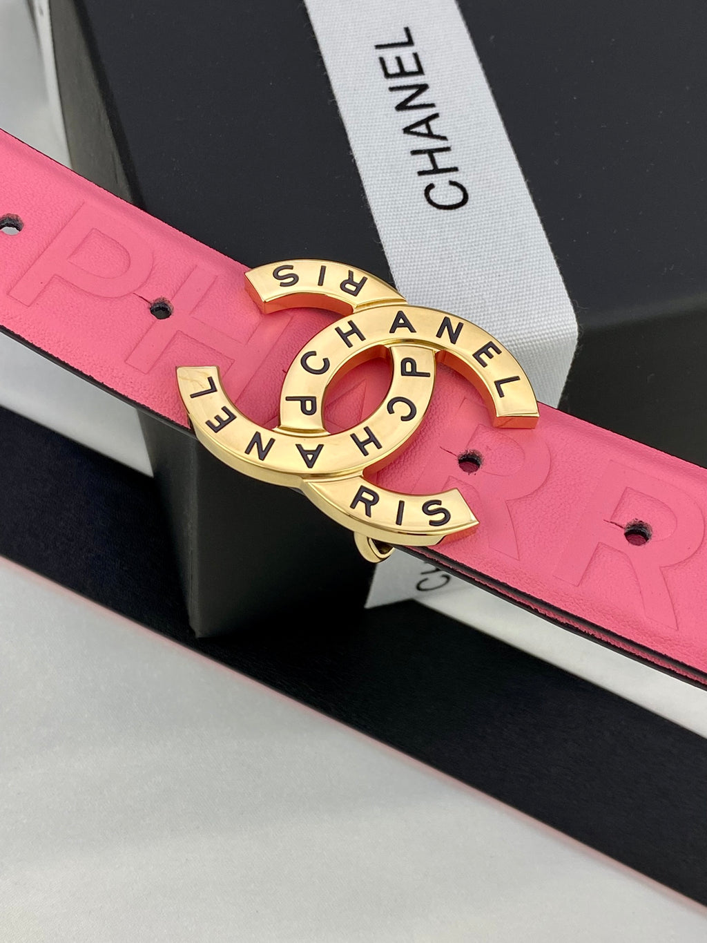 Pink Chanel belt close-up: embossed strap and gold circular Chanel logo buckle