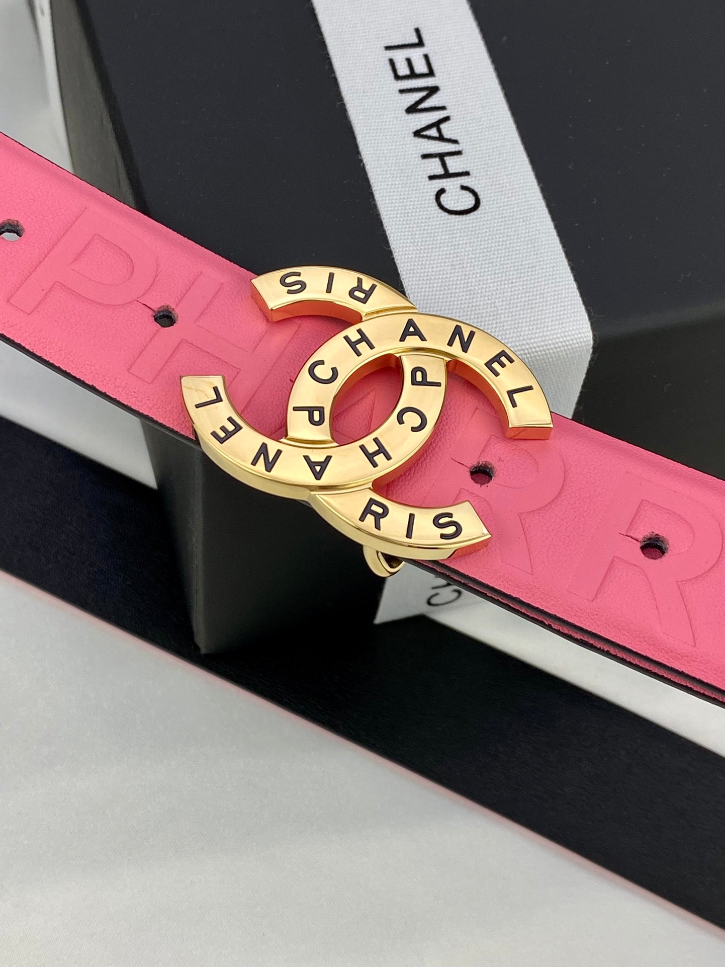 Pink Chanel belt close-up: embossed strap and gold circular Chanel logo buckle